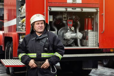 İtfaiyeci (itfaiye) eylem daimi bir firetruck yakınındaki. Acil durum Emanet. Koruma, tehlikeden kurtarmak.