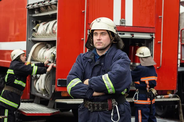 İtfaiyeci (itfaiye) eylem daimi bir firetruck yakınındaki. Acil durum Emanet. Koruma, tehlikeden kurtarmak.