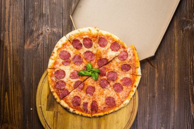 Mozzarella peyniri, salam ve roka kutusunda ahşap zemin üzerine biberli pizza