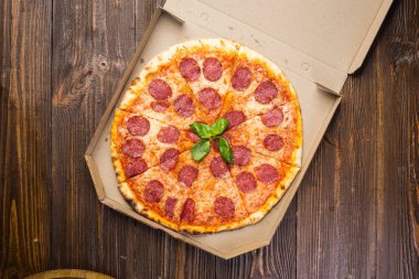 Mozzarella peyniri, salam ve roka kutusunda ahşap zemin üzerine biberli pizza