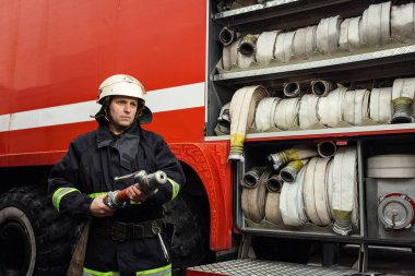 İtfaiyeci (itfaiye) eylem daimi bir firetruck yakınındaki. Acil durum Emanet. Koruma, tehlikeden kurtarmak.
