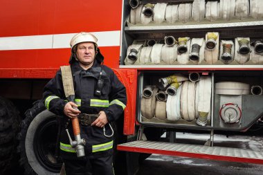 İtfaiyeci (itfaiye) eylem daimi bir firetruck yakınındaki. Acil durum Emanet. Koruma, tehlikeden kurtarmak.