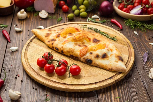 Geleneksel İtalyan kapalı pizza Calzone fesleğen ile ahşap arka plan üzerinde bırakır