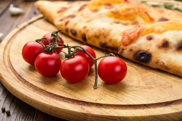 Geleneksel İtalyan kapalı pizza Calzone fesleğen ile ahşap arka plan üzerinde bırakır