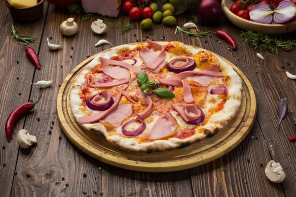 Lezzetli İtalyan pizza jambon, sosis ve fesleğen tarafından dekore edilmiş soğan ile ahşap arka plan üzerinde bırakır