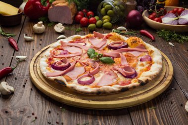 Lezzetli İtalyan pizza jambon, sosis ve fesleğen tarafından dekore edilmiş soğan ile ahşap arka plan üzerinde bırakır