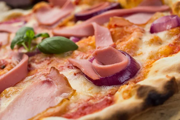 Lezzetli İtalyan pizza jambon, sosis ve fesleğen tarafından dekore edilmiş soğan ile ahşap arka plan üzerinde bırakır