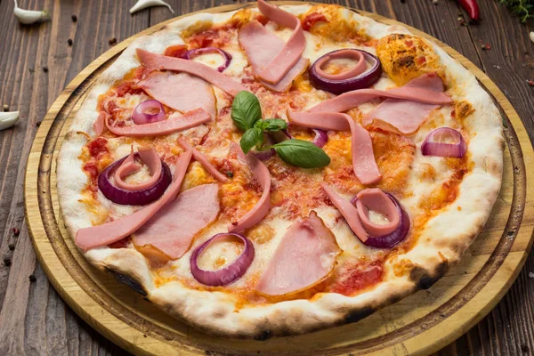 Lezzetli İtalyan pizza jambon, sosis ve fesleğen tarafından dekore edilmiş soğan ile ahşap arka plan üzerinde bırakır