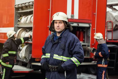 İtfaiyeci (itfaiye) eylem daimi bir firetruck yakınındaki. Acil durum Emanet. Koruma, tehlikeden kurtarmak.