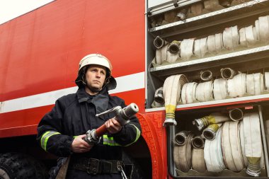 İtfaiyeci (itfaiye) eylem daimi bir firetruck yakınındaki. Acil durum Emanet. Koruma, tehlikeden kurtarmak.