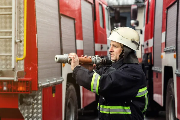 İtfaiyeci (itfaiye) eylem daimi bir firetruck yakınındaki. Acil durum Emanet. Koruma, tehlikeden kurtarmak.