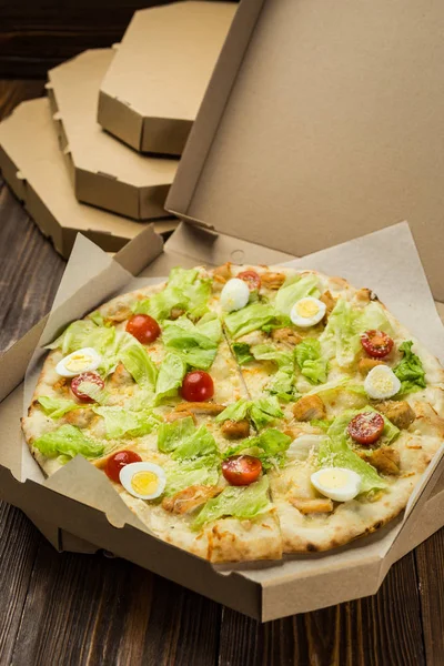 Pizza Caesar with chicken and tomatoes in box on wooden background