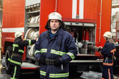İtfaiyeci (itfaiye) eylem daimi bir firetruck yakınındaki. Acil durum Emanet. Koruma, tehlikeden kurtarmak.