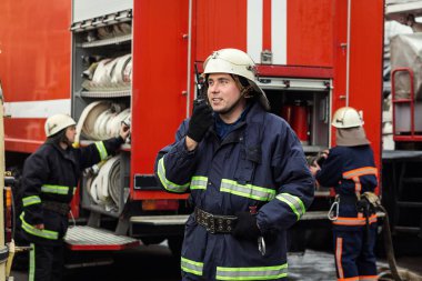İtfaiyeci (itfaiye) eylem daimi bir firetruck yakınındaki. Acil durum Emanet. Koruma, tehlikeden kurtarmak.