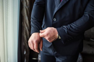 İş adamı ceket giyiyor, erkek eli kapalı, damat düğün töreninden önce hazırlanıyor.