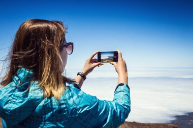 Tenerife, Kanarya Adaları, İspanya üzerinde fotoğrafta telefonunu şaşırtıcı dağlar peyzaj ile genç bir kadın. Seyahat kavramı