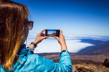 Tenerife, Kanarya Adaları, İspanya üzerinde fotoğrafta telefonunu şaşırtıcı dağlar peyzaj ile genç bir kadın. Seyahat kavramı