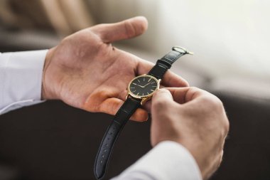 İş adamı kol saatini kontrol ediyor, saati eline alıyor, damat düğün töreninden önce hazırlanıyor.