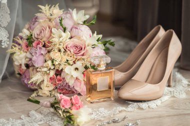 bir masaya gelin aksesuar ayakkabı, küpe, buket ve parfüm gibi yalan