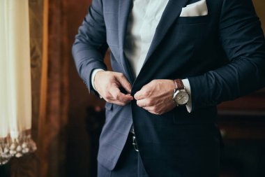 İş adamı ceket giyiyor, erkek eli kapalı, damat düğün töreninden önce hazırlanıyor.