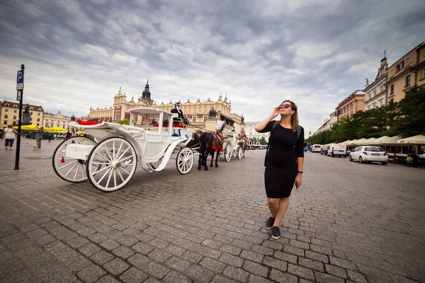 年轻而快乐的女游客走在欧洲老城克拉科夫的市场广场上 欧洲各地的旅行 — 图库照片