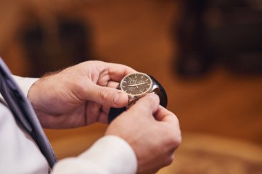 İş adamı kol saatini kontrol ediyor, saati eline alıyor, damat düğün töreninden önce hazırlanıyor.