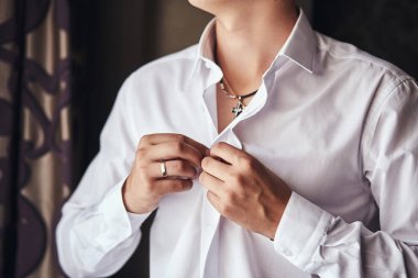 İş adamı beyaz gömlek giyer, erkek eli yakın durur, damat düğün töreninden önce sabah hazırlanır.