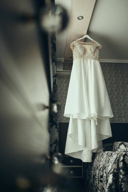 Güzel gelinlik odada asılı, kadın törenden önce hazırlanıyor.