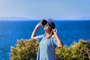 Bodrum, Türkiye'de güneşli gün, mavi gökyüzü ile deniz manzaralı zevk plaj şapkalı güzel bir kadın. Tatil açık havada deniz manzarası yaz seyahat kavramı