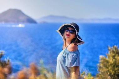 Bodrum, Türkiye'de güneşli gün, mavi gökyüzü ile deniz manzaralı zevk plaj şapkalı güzel bir kadın. Tatil açık havada deniz manzarası yaz seyahat kavramı