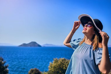 Bodrum, Türkiye'de güneşli gün, mavi gökyüzü ile deniz manzaralı zevk plaj şapkalı güzel bir kadın. Tatil açık havada deniz manzarası yaz seyahat kavramı