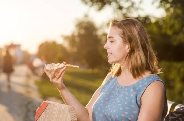 Sıcak pizza kutusunda, koltukta park açık tutan mutlu genç kadın