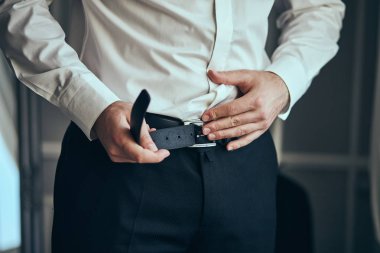 İş adamı kemer takıyor, moda ve giysi konsepti, damat törenden önce sabah hazırlanıyor.