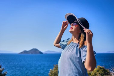 Bodrum, Türkiye'de güneşli gün, mavi gökyüzü ile deniz manzaralı zevk plaj şapkalı güzel bir kadın. Tatil açık havada deniz manzarası yaz seyahat kavramı