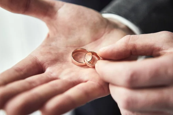 Homem segurando anéis de casamento, noivo se preparando pela manhã antes da cerimônia — Fotografia de Stock