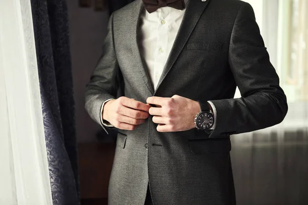 El hombre de negocios lleva una chaqueta, las manos masculinas se acercan, el novio se prepara en la mañana antes de la ceremonia de boda. Moda de hombres — Foto de Stock