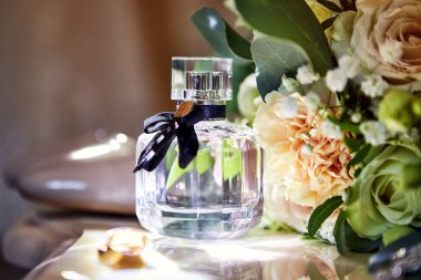 Ayakkabı, buket, yüzük ve parfüm gibi düğün aksesuarları bir masanın üzerinde bulunur.