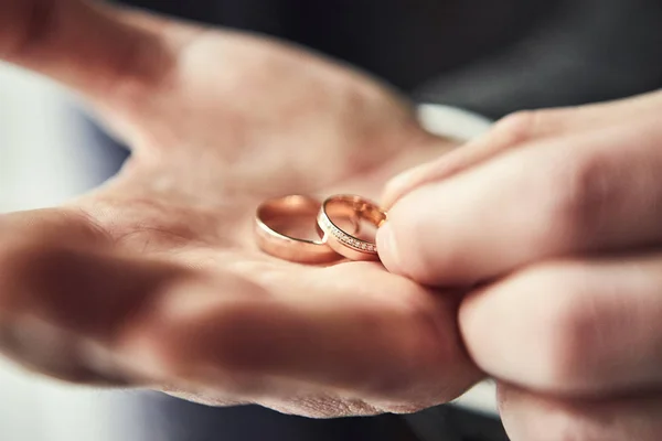 Homem segurando anéis de casamento, noivo se preparando pela manhã antes da cerimônia — Fotografia de Stock