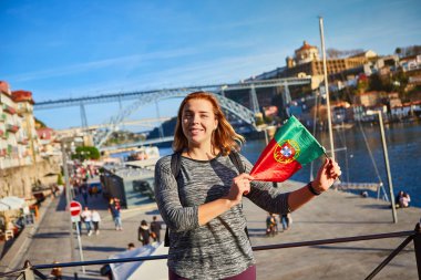 Portekiz bayrağı ile ayakta, Porto, Portekiz ışık sabah saatlerinde Douro nehir, köprü ve tekneler güzel cityscape manzarasının tadını genç kadın Gezgin 