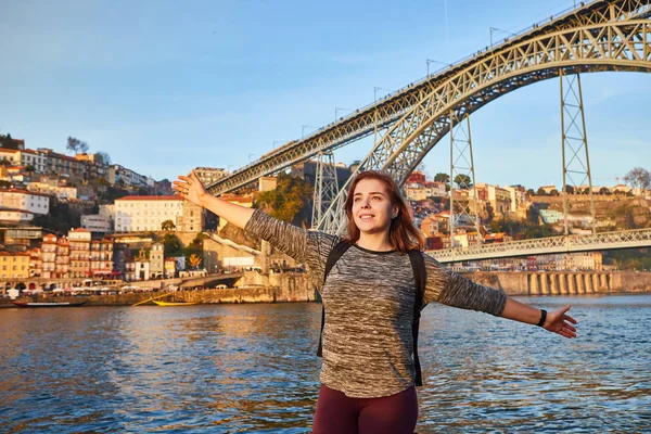 Joven turista disfrutando de una hermosa vista del paisaje en el casco antiguo con río y famoso puente de hierro Dom Luiz durante la puesta de sol en la ciudad de Oporto, Portugal — Foto de Stock