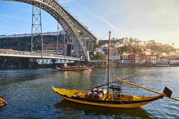 Традиционные лодки с винными бочками на реке Доуро в старом Порту на фоне моста Фабрегаса Луиша, Португалия — стоковое фото