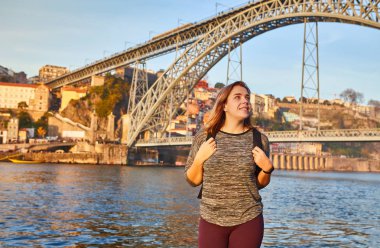 Güzel manzara nehir ve ünlü Demir köprü Dom Luiz eski beldesi üzerinde gün batımı sırasında Portekiz Porto şehir içinde manzarayı genç kadın turist