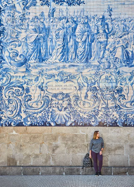 Young woman tourist walking near the church with famous portuguese blue ceramic tiles on the facade traveling in Porto city, Portugal — Stock Photo, Image