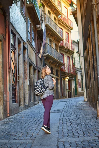 Ung kvinna traveler promenader genom de gamla gatorna i staden i Porto, Portugal — Stockfoto