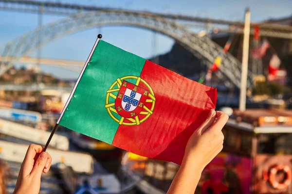 Portugalski flaga jako symbol Portugalii na tle mostu Ponte de Dom Luis I na nasyp w pobliżu rzeki Doure w Porto — Zdjęcie stockowe