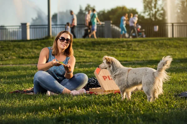 Щаслива молода жінка тримає гарячу піцу в коробці, сидіння відкривається в парку — стокове фото