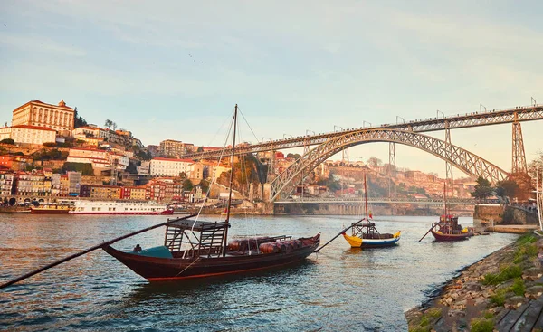 Традиционные лодки с винными бочками на реке Доуро в старом Порту на фоне моста Фабрегаса Луиша, Португалия — стоковое фото