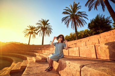 Bodrum, Türkiye'nin güneşli bir günde, bir antik amfitiyatro basamaklarında oturan plaj şapka genç güzel kadın. Tatil açık havada deniz manzarası yaz seyahat kavramı 