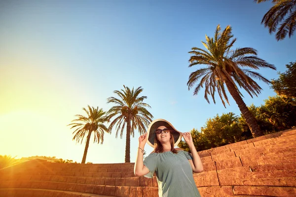 在土耳其博德鲁姆阳光明媚的日子里, 戴着沙滩帽子走在古老圆形剧场台阶上的年轻美丽的女人。户外度假海景夏季旅游概念 — 图库照片