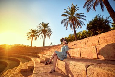 Bodrum, Türkiye'nin güneşli bir günde, bir antik amfitiyatro basamaklarında oturan plaj şapka genç güzel kadın. Tatil açık havada deniz manzarası yaz seyahat kavramı 